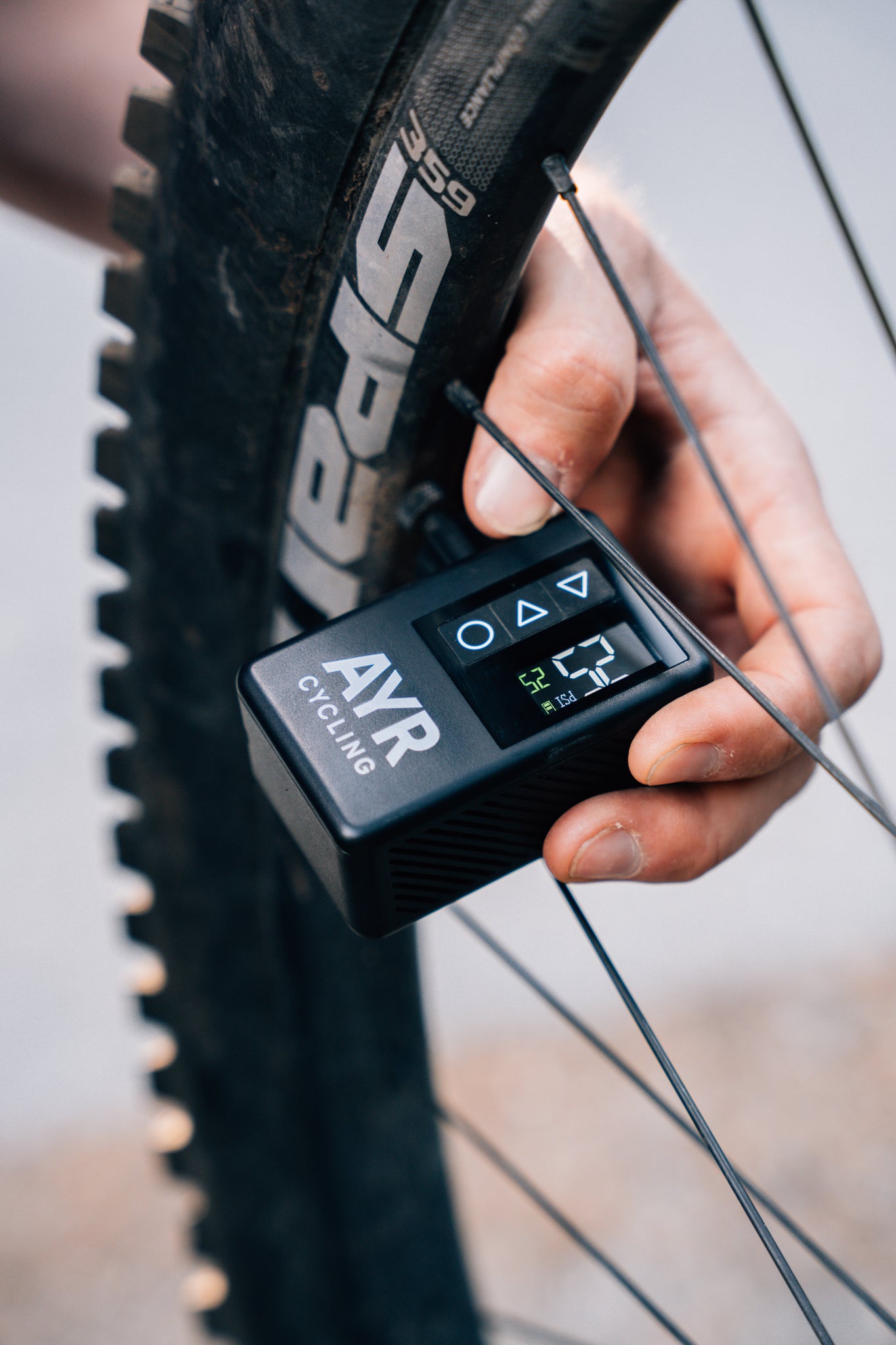 AYR Cycling electric pump inflating a mountain bike tire, showing digital PSI display in use