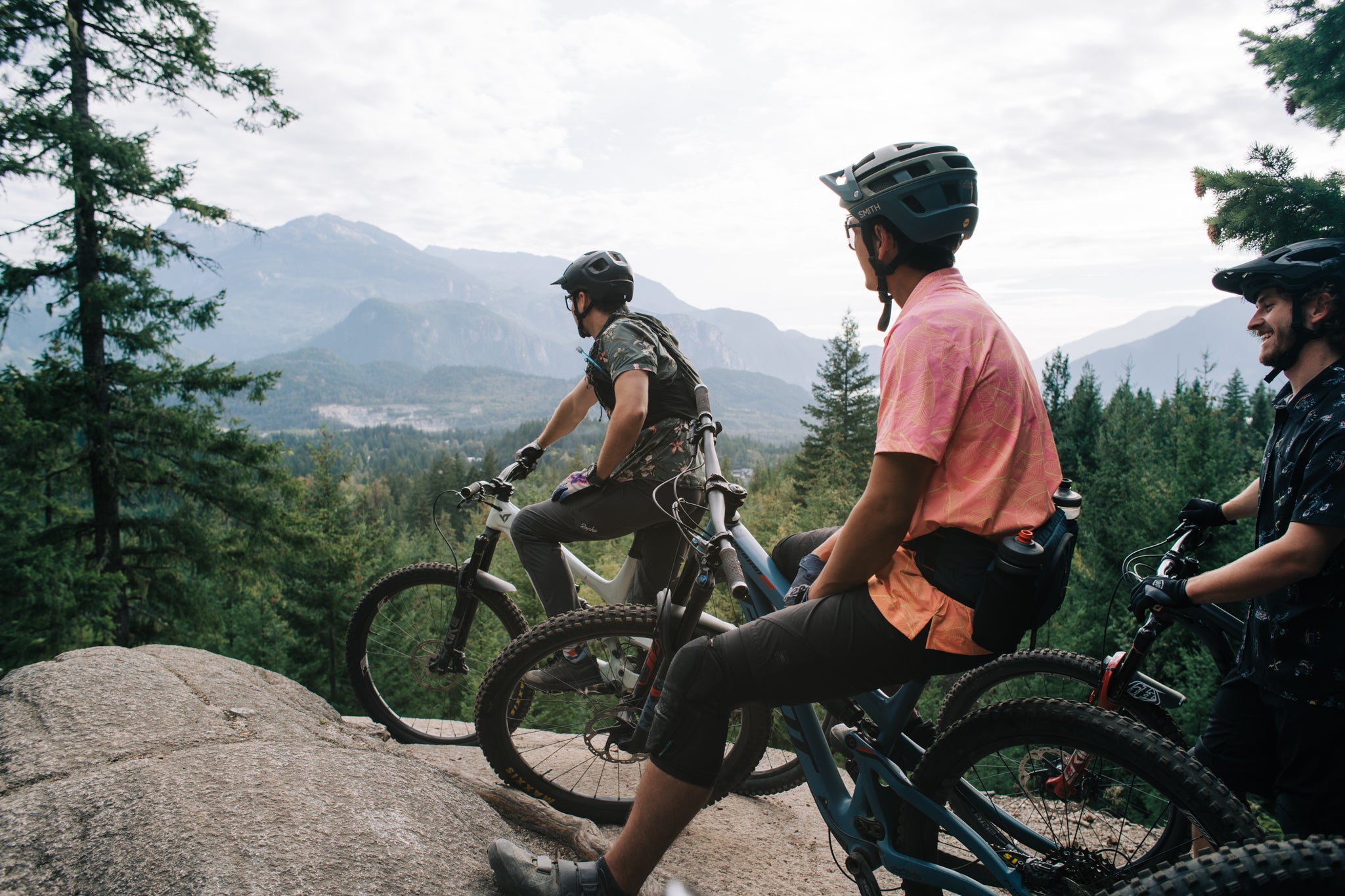 Group of mountain bikers overlooking forested trails and mountains in Squamish, British Columbia