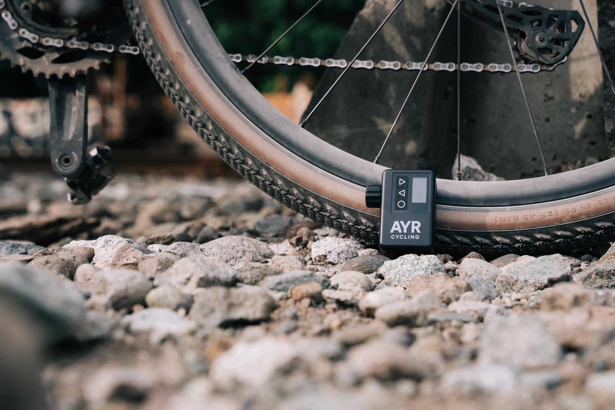 AYR Cycling E-Pump leaning against a gravel bike tire on a rocky trail